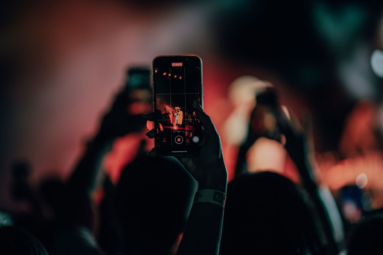 ステージの上演をスマートフォンやカメラで撮影する観客の手元